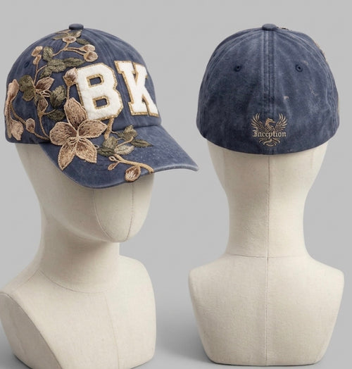 Two denim baseball caps on mannequin heads with floral and letter designs.